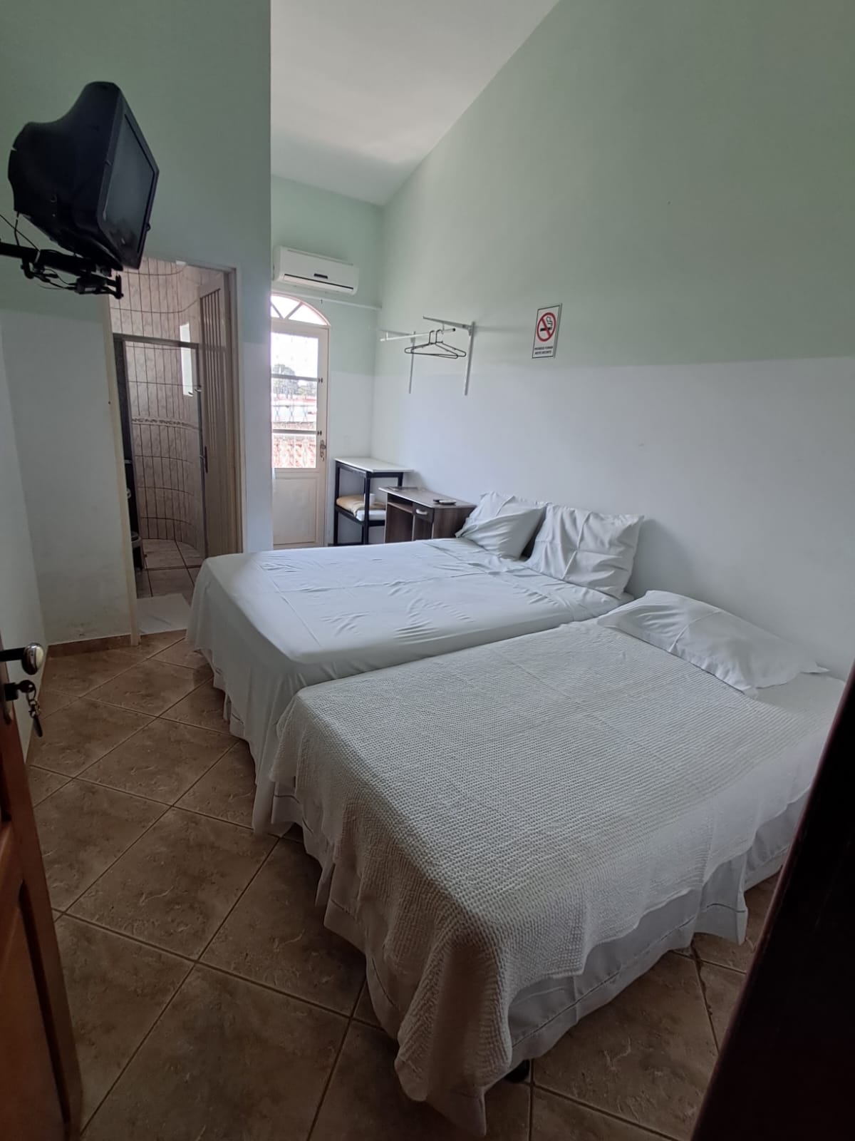 Quarto com cama de casal, cama de solteiro e televisão